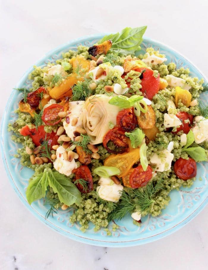 Pesto quinoa salad dressed in a vegan basil pesto and topped with oven roasted cherry tomatoes, artichokes, roasted bell peppers and pine nuts.