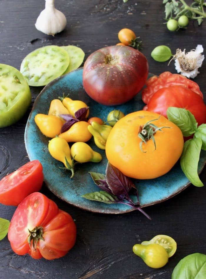 Mixed colors heirloom tomatoes, basil and garlic.