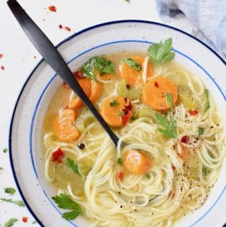 Vegan vegetable noodle soup with long angel hair noodles, carrots, celery and parsley.