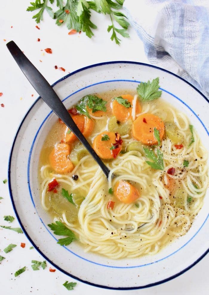 Vegan vegetable noodle soup with long angel hair noodles, carrots, celery and parsley.