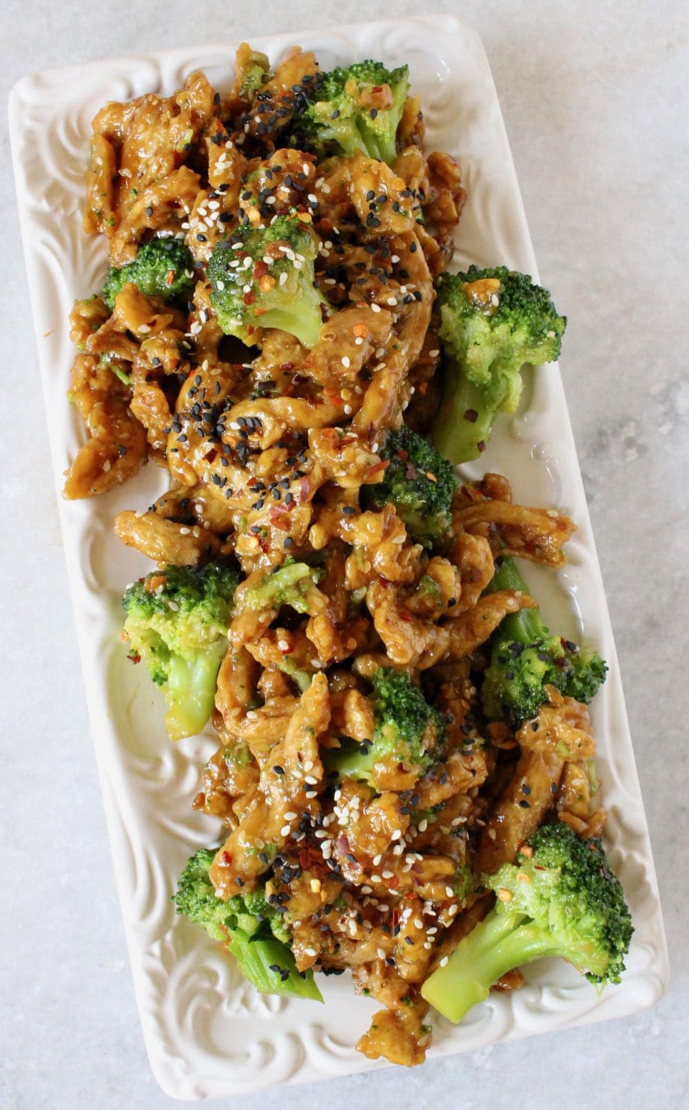 Vegan chicken with broccoli in a homemade garlic ginger sauce on white serving platter.